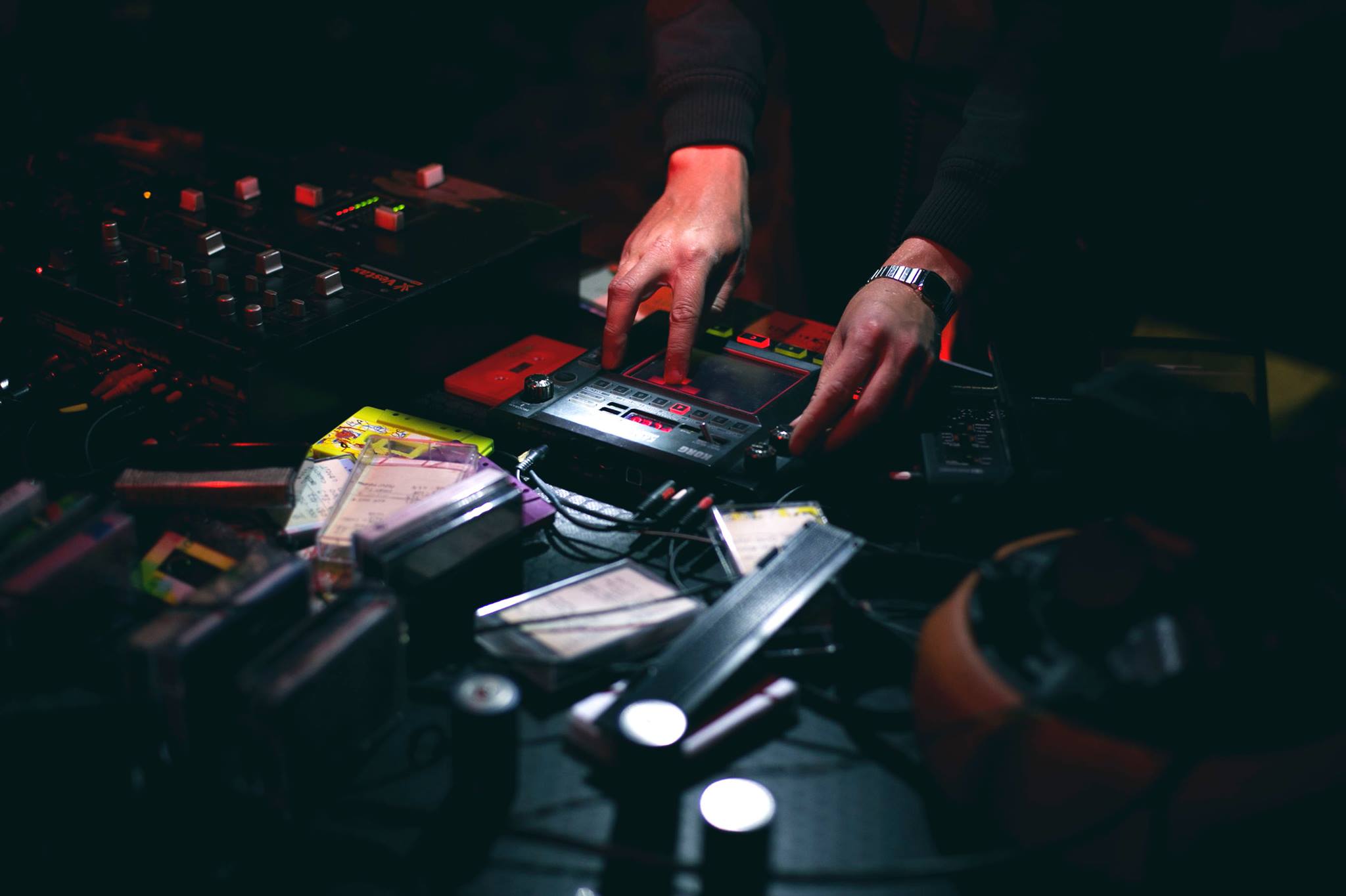 Fotografia kolorowa. Kadr na dłonie pracujące przy elektronicznym sprzęcie do tworzenia muzyki.