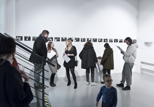 Zdjęcie, kilkoro zebranych uczestników podczas wernisażu artystki Hélène Thiennot pod tytułem „Nieobecne”, w przestrzeni Sali wystawienniczej w CSW ŁAŹNIA 1 na Dolnym Mieście. 
