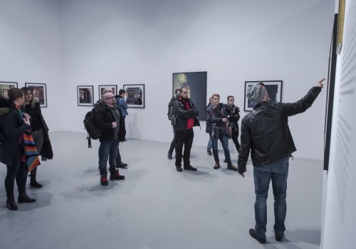 Zdjęcie, licznie zebrani uczestnicy oglądają prezentowane prace artysty we wnętrzu Sali Wystawienniczej.