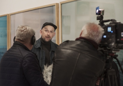 Zdjęcie, zbliżenie na Michała Szlagę udzielającego wywiadu przed kamerą.