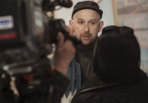 Zdjęcie, zbliżenie na Michała Szlagę udzielającego wywiadu przed kamerą.