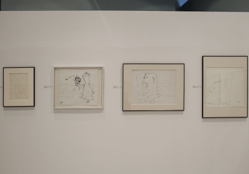Zdjęcie, dokumentacja wystawy prac Franciszki Themerson pod tytułem „Linie życia”. Na białej ścianie Sali Wystawienniczej prezentowane są cztery ilustracje artystki.
