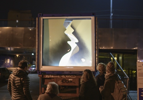 Kadr na szybę galerii LKW z widoczną instalacją artystyczną autorstwa Pauliny Grosz. Dookoła widoczne postacie odwiedzających.