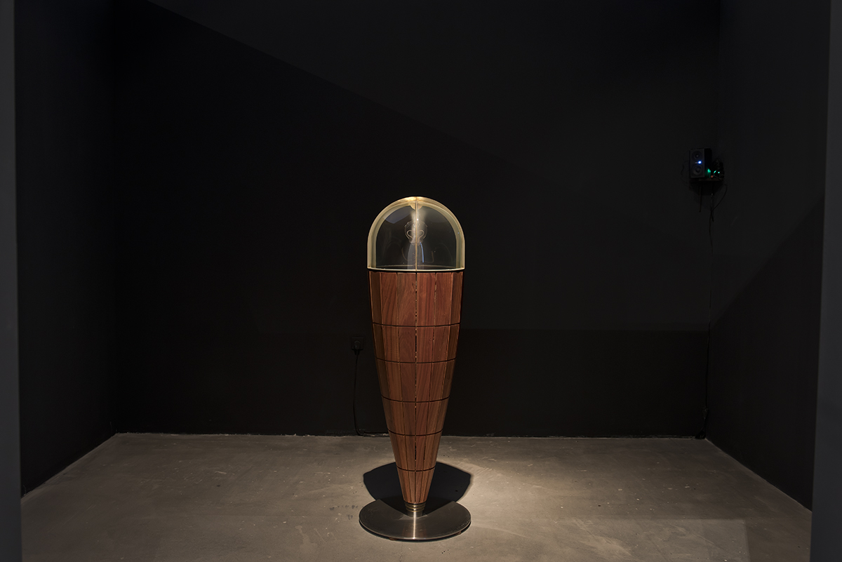 Instalacja artystyczna przypominająca odwrócony, drewniany stożek zwieńczony szklaną kopułą.