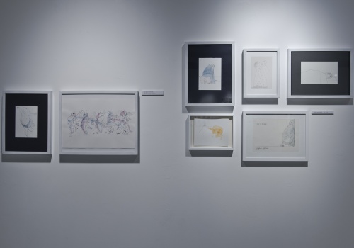 Zdjęcie, zbliżenie na cześć ilustracji artysty, które prezentowane są na ścianie Sali wystawienniczej.