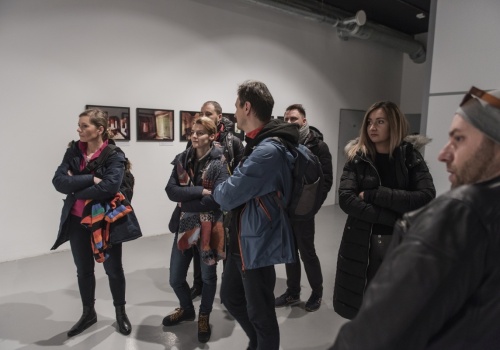 Zdjęcie, uczestnicy wernisażu oglądają pracę artysty. Po prawej stronie kadru znajduje się Jerzy Wierzbicki.