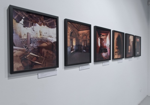 Zdjęcie, zbliżenie na ścianę Sali Wystawienniczej. Na ścianie prezentowane są fotografie Jerzego Wierzbickiego.