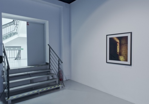 Zdjęcie, po lewej stronie kadru znajduje się wejście do Sali Wystawienniczej, a po prawej stronie prezentowana jest fotografia Jerzego Wierzbickiego.