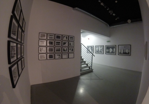 Sala wystawiennicza z licznymi pracami autorstwa Adrei Mastrovito rozmieszczonymi w równych rzędach i kolumnach, ukazujące kadry z filmów z pomalowanymi na biało postaciami. 