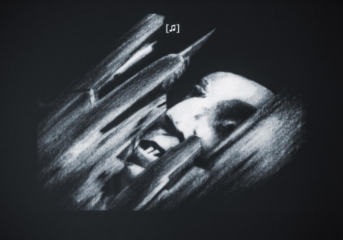 Rysunek przedstawiający wyłaniającą się gargantuiczną twarz Nosferatu spomiędzy strzelistych budowli.