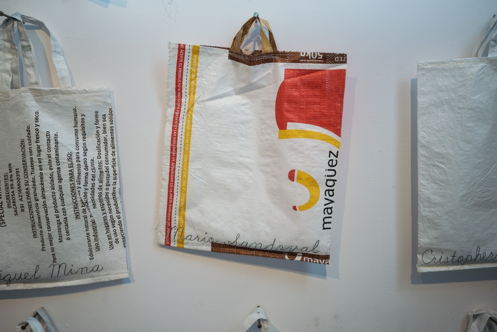 Zbliżenie na jedną z zawieszonych na ścianie plastikowych toreb, z próbką gleby w środku. 
