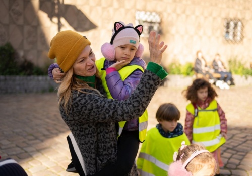 Zbliżenie na kuratorkę CSW Łaźnia, Annę Szynwelską, z dzieckiem na rękach. Obok stoją inne dzieci.