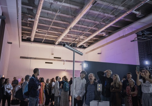  Zdjęcie. Przestrzeń wystawy. Duża grupa ludzi oglądająca pracę Londona Tsai’a „Czarne czy Białe? Ying czy Yang?” .